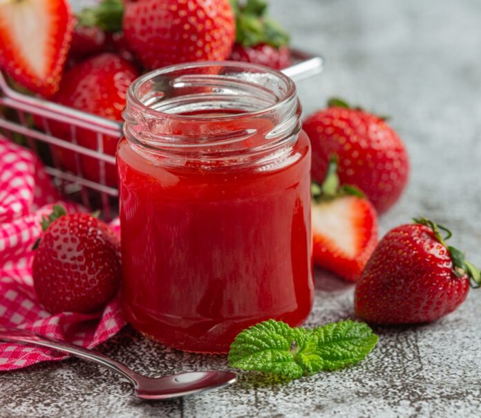 Strawberry jam on old dark background